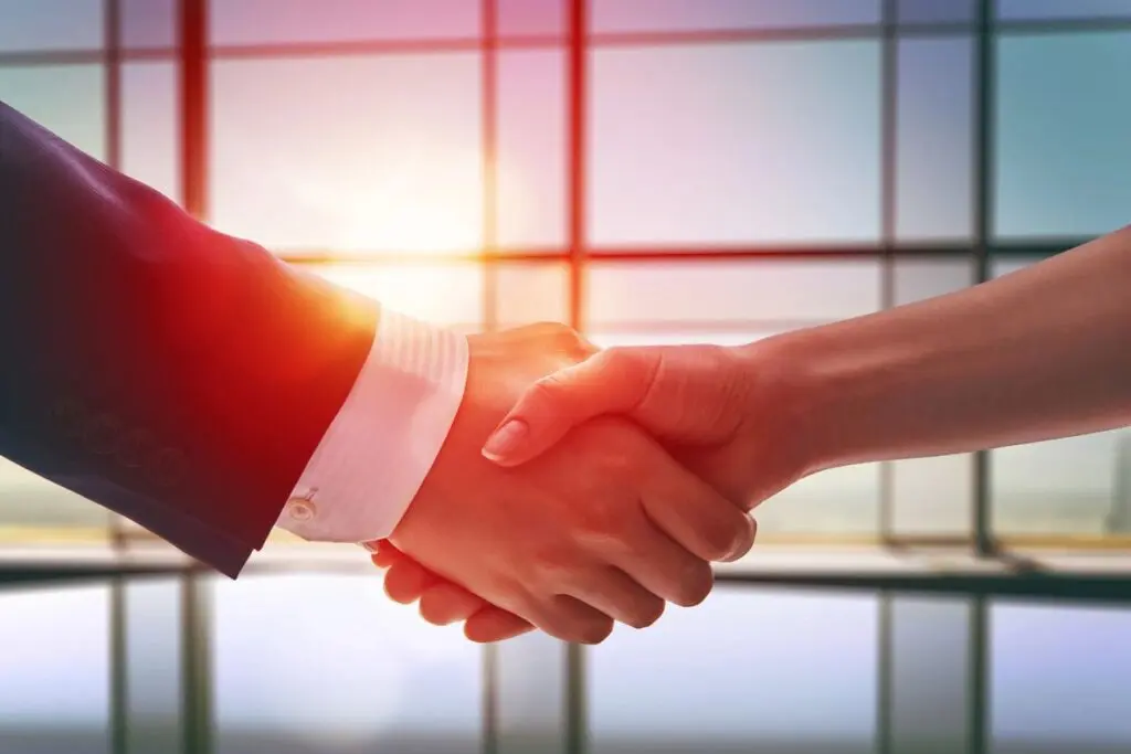 Two people shaking hands in front of a window.